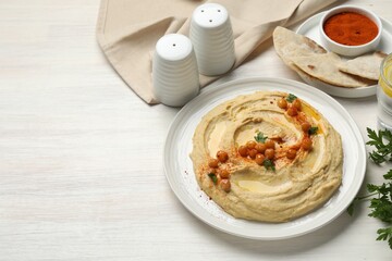 Delicious hummus with olive oil, chickpeas and paprika served on white wooden table, space for text