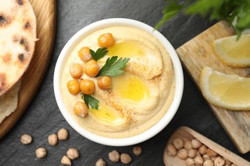 Delicious hummus with olive oil and chickpeas served on grey textured table, flat lay