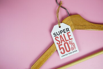 Super Sale 50% on price tag with wooden clothes hanger top view on pink background