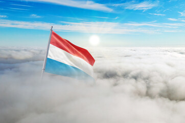 Luxembourg flag aerial view in beautiful sky with clouds. Top-down drone shot at sunrise or sunset. Aerial bird's eye view of the flag with cloudscape.