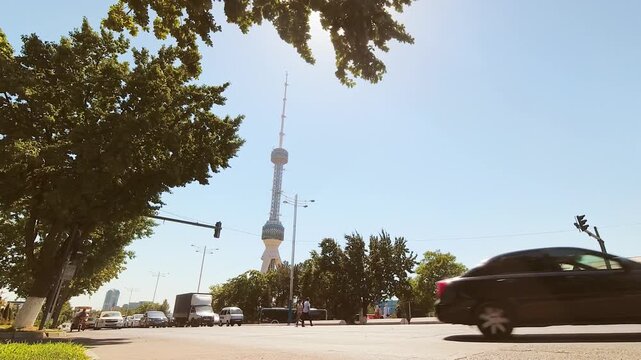 Tashkent, Uzbekistan - 13th november, 2023: zoom in view vehicles drive in capital city traffic in hot sunny summer day on rush hour with Taskent city TV tower background. Transportation concept