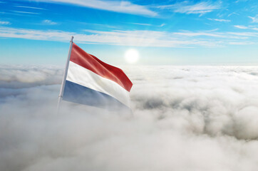 Naklejka premium Netherlands flag aerial view in beautiful sky with clouds. Top-down drone shot at sunrise or sunset. Aerial bird's eye view of the flag with cloudscape.