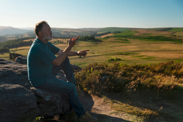 Man Sitting on Rock Outcrop Overlooking Rolling Green Valley