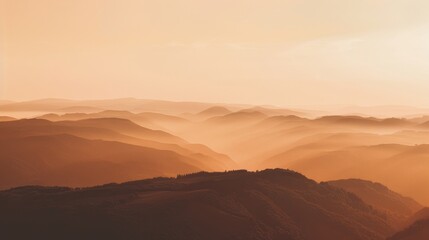 Obraz premium A breathtaking view of a mountain range bathed in the warm glow of the setting sun, with layers of mountains and fog creating a sense of depth and serenity. The image embodies tranquility, natural bea