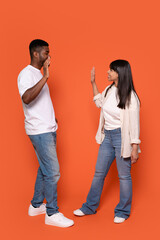 Man and Woman Giving Each Other  High Five Against Orange Background