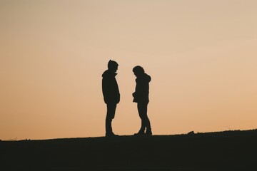 Fototapeta premium Two figures standing opposite each other in the evening light Concept conversation relationship evening digital art