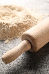 Rolling pin and scattered flour on grey textured table, closeup