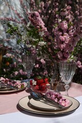 Stylish table setting with beautiful spring flowers in garden