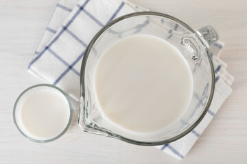 Jug and glass of fresh milk on wooden table, top view