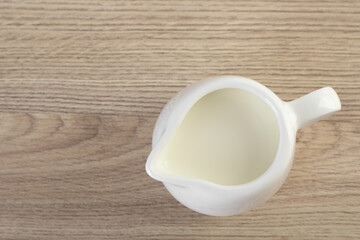 Jug of fresh milk isolated on wooden table, top view. Space for text