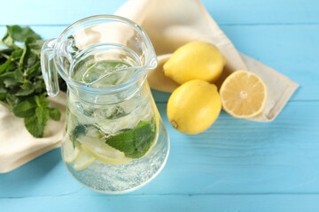 Fototapeta premium Refreshing lemonade with mint in jug and ingredients on light blue wooden table