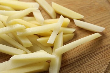 Cut fresh raw potatoes on wooden table, closeup