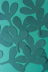 overlapping stylized paper leaves die-cut from dark green paper on blank green paper