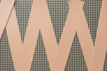 pearly pastel orange paper strips on scrapbooking paper with plaid pattern