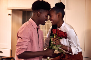 Black people, couple and forehead touch with flowers for love, care and support on valentines day. Home, relationship and happy with roses a gift or present for romance with anniversary celebration