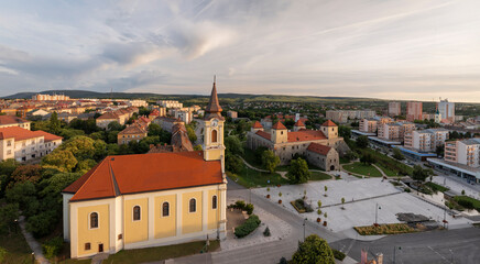 Fototapeta premium Aerial view of Varpalota Thury castle with newly renovated red orange roof, four rectangular towers in the middle of the former mining town with communist block houses in the background.