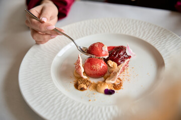 Top view of female hand holding spoon and going to eat tasty dessert in the restaurant