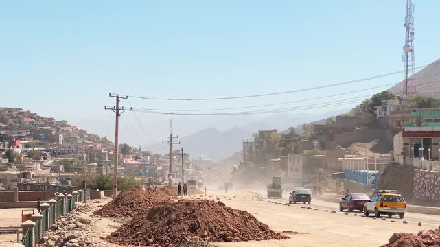 Kabul, Afghanistan - 20 th october, 2023: Vehicles drive on dusty asphalt road. Kabul capital cityscape in sunny day. Road construction works in summer