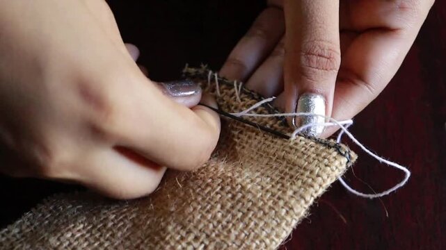 Women sewing jute febric by hand at home, handmade art. 