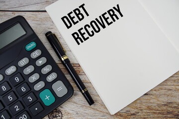 Debt recovery text on notebook page with alarm clock top view on wooden background