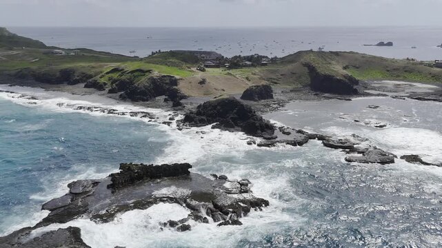 Drone flies to the right over water facing Buraco da Raquel and Enseada dos Tubar&otilde;es at low tide, with boats scattered in the Porto do Santo Antonio in the background