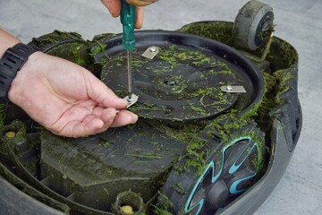 A man changes the blades of a robotic lawn mower.