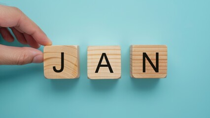 January word on wooden block in month date concept with light blue background.