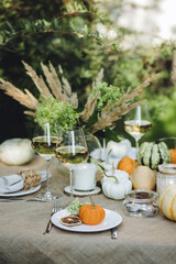 Simple craft elements, pumpkins as decoration, candles. Lunch outdoors in the garden. Cozy dinner table decor for an autumn event, countryside party, thanksgiving dinner or wedding.