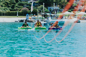 Friends enjoying speedboat tubing adventure on a sunny day in crystal clear blue water