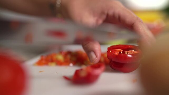 manos en c&aacute;mara lenta cortando aj&iacute; picante en trozos peque&ntilde;os 