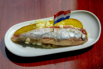 Selective focus of Soused herring (Hollandse Nieuwe) served with diced onions and sliced pickled on the side, Typical Dutch delicacy and popular street food in summer, Preserving food in Netherlands.