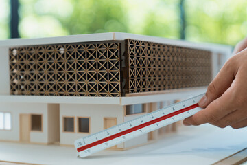 Closeup of professional architect hand measuring house model by using ruler and architectural...