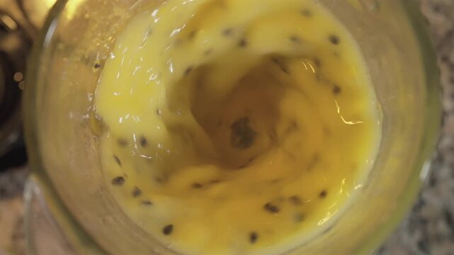 Licuadora girando con pulpa de maracuy&aacute; para jugo en vaso de vidrio 