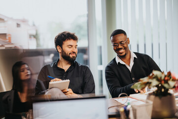 Two business colleagues sharing a joyful moment in a meeting room, indicating positive workplace culture and effective collaboration.