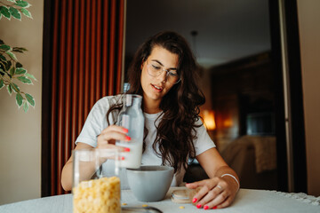 Young caucasian woman eating corn flakes for breakfast