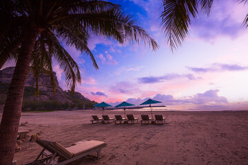 Beaches and sunbathing tables in Thailand Rows of empty sun loungers and orange parasols on a tropical beach at sunset. Vacation in an all inclusive hotel on the sea in Thailand