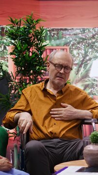 Vertical Video Nurse jumping to help senior man in wheelchair losing conscience during home visit, old person hyperventilating and scaring his wife. Medical assistant in panic checking the pulse