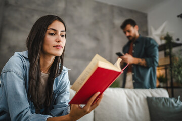 Adult young woman sit and read a book in the living room