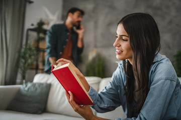 Adult young woman sit and read a book in the living room