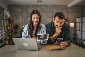 happy couple in love hold ultrasound picture of their first baby