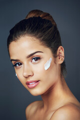 Naklejka premium Cream, skincare and woman with portrait in studio for facial treatment, natural cosmetics or dermatology on gray background. Wellness, beauty and model with product for moisturizer, lotion or glow