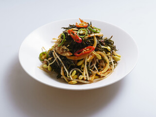 Close-up of seasoned seaweed(hizikia fusiforme) with bean sprouts and red peppers on dish, South Korea
