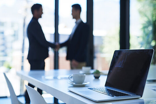 Laptop, business people and handshake for deal in office with partnership, onboarding and hiring meeting. Professional, employees or shaking hands in boardroom for welcome, promotion and introduction