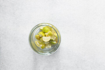 Overhead view of Lime cheong in a glass jar on a white background, top view of korean lime cheong in a transparent jar, limes in sugar syrup, process of making lime cheong