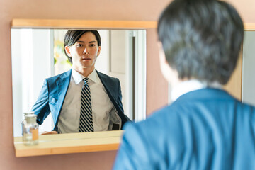 洗面所で身支度するスーツ姿の若い男性ビジネスマン
