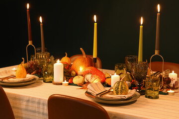 Festive table setting for Thanksgiving day with pumpkins and burning candles at evening