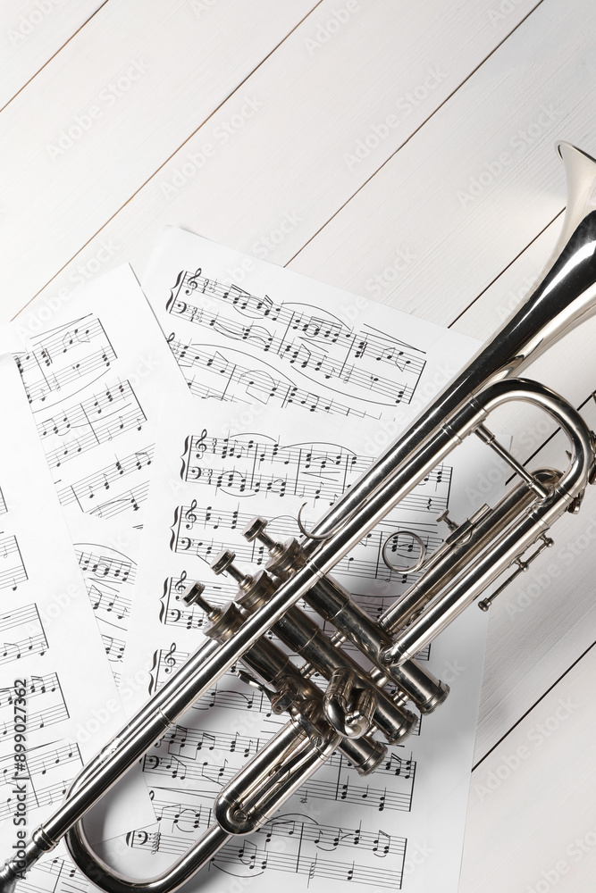 Poster Trumpet and music sheet papers with notes on white wooden table, flat lay