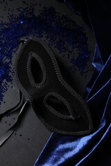 Obraz premium Beautiful carnival mask and blue sequins on black table, closeup
