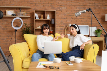 Young women with laptop recording podcast at home