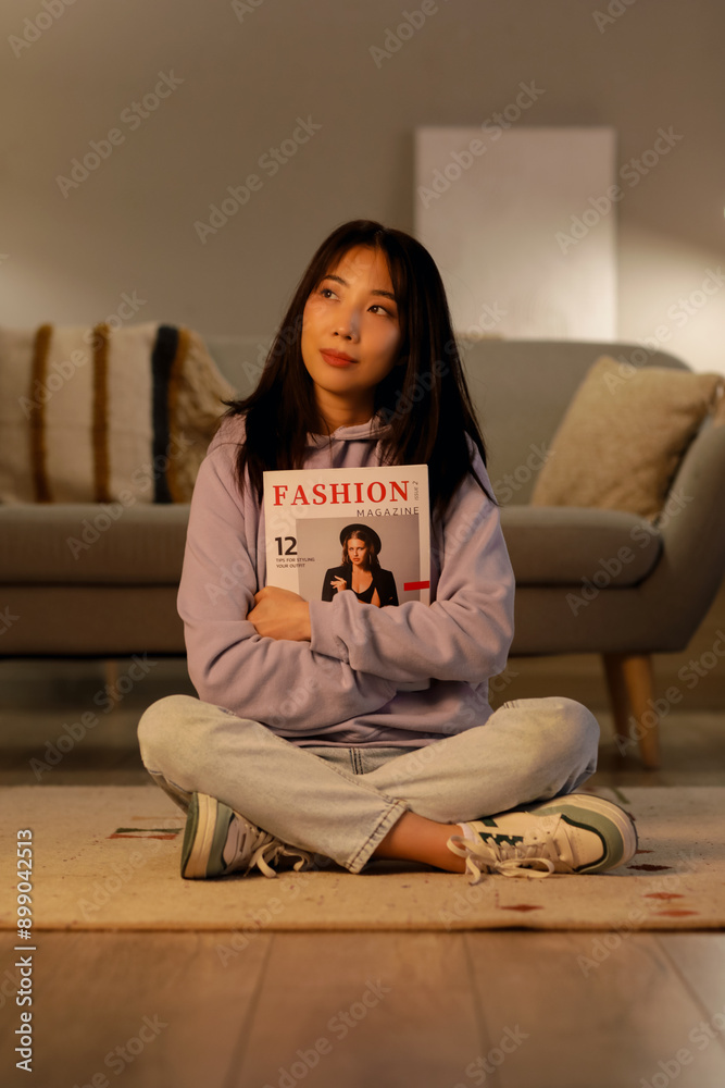 Sticker Young Asian woman with magazine in living room